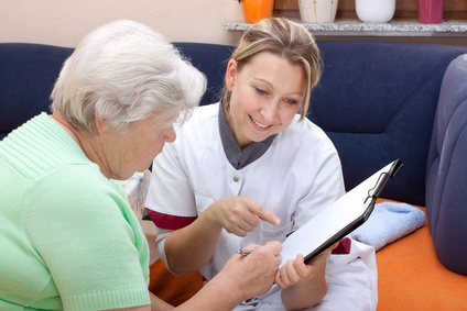 Seniorin und Pflegerin sitzen beieinander